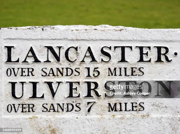 an old road sign giving distances to towns across the sands of morecambe bay in cartmel, cumbria, uk. - lancaster lancashire stock-fotos und bilder