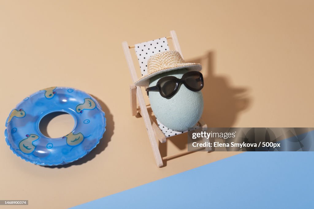 A cheerful Easter composition with an egg in sunglasses lies on a sun lounger on the beach,Moscow,Russia