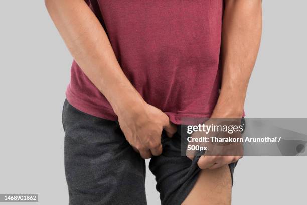 midsection of man holding aching pockets standing against white background - leistenregion stock-fotos und bilder