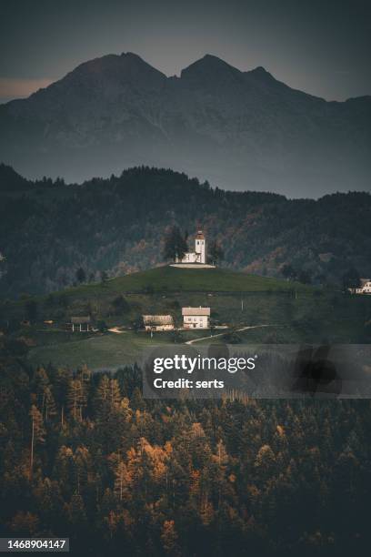 landscape view  with sveti tomaz church (saint thomas) or church (cerkev sveti tomaz) in beautiful sunrise in autumn, near skofja loka in the upper carniola region, slovenia, europe - triglav slovenia stock pictures, royalty-free photos & images