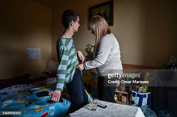 Ina, age 47 who is from Dnipro Oblast helps her son, Jaroslaw, age 19 who suffers from with a chronic illness in their room at the Green Hotel on...