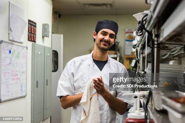 cheerful male chef cleans up kitchen after long day - person of colour stock pictures, royalty-free photos & images