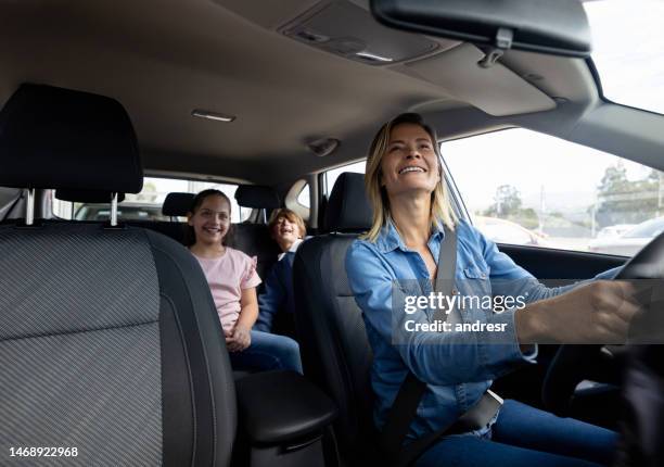 happy mother driving her kids in her car - car interior stock pictures, royalty-free photos & images