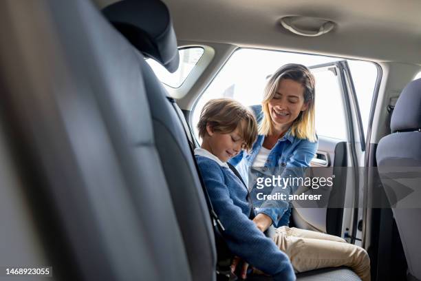mother fastening the seat belt of her son in the back seat of a car - child car seat stock pictures, royalty-free photos & images