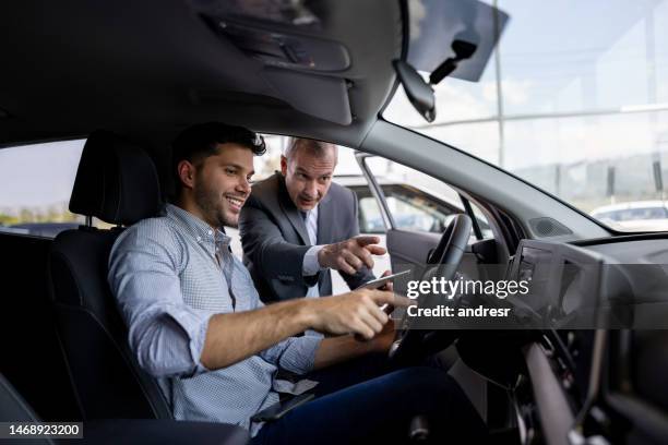 verkäufer zeigt den innenraum des autos einem mann, der beim autohaus einkauft - car ownership stock-fotos und bilder