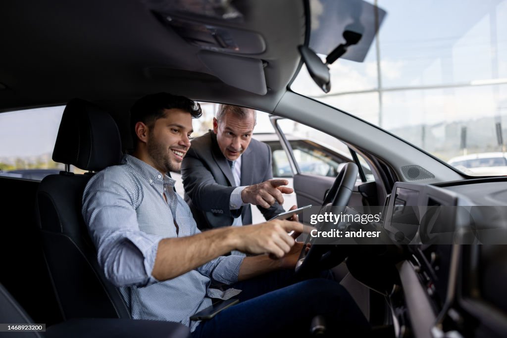 Salesman showing the car interior to a man shopping at the dealership