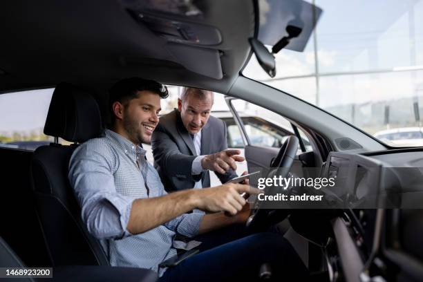 salesman showing the car interior to a man shopping at the dealership - buying a car 個照片及圖片檔