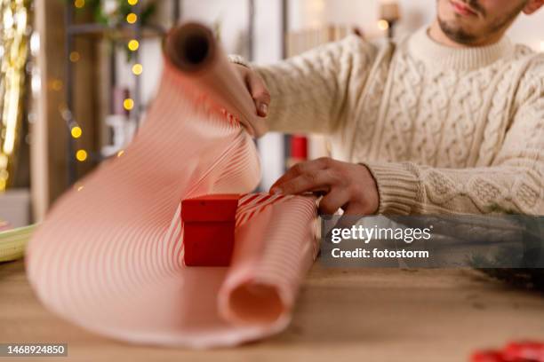 man wrapping a little red gift box in a wrapping paper - roll of wrapping paper stock pictures, royalty-free photos & images