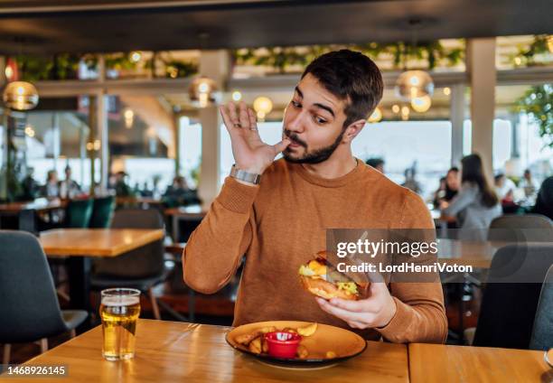 young man enjoying a delicious burger - lamber imagens e fotografias de stock