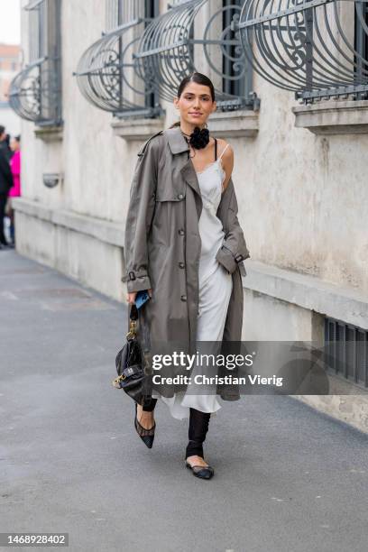 Nika Kes wears grey coat, satin dress, black bag outside Prada during the Milan Fashion Week Womenswear Fall/Winter 2023/2024 on February 23, 2023 in...