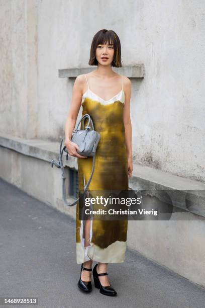 Elva Ni wears brown yellow dress with slit, bag outside Prada during the Milan Fashion Week Womenswear Fall/Winter 2023/2024 on February 23, 2023 in...