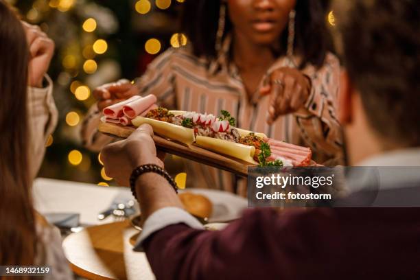 friends enjoying drinks, delicious food and chatting casually during a christmas dinner party - charcuterie stock pictures, royalty-free photos & images