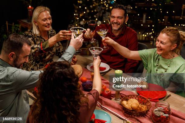 friends cheering with drinks to health and happiness during a christmas dinner party - cocktail party at home stock pictures, royalty-free photos & images