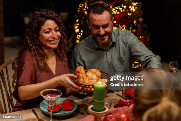woman serving bread buns for her friends at the dining table during a christmas dinner party - christmas party host stock pictures, royalty-free photos & images
