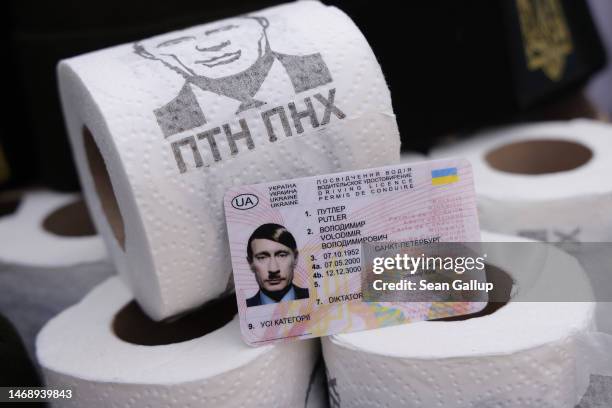 Rolls of toilet paper depicting Russian President Vladimir Putin stand on a table along with a fake driver's licence for Putin that names him as...