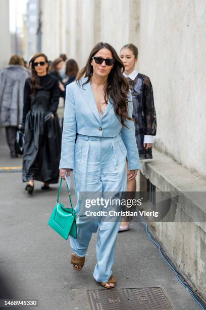 Guest wears satin turquoise suit, green bag outside Prada during the Milan Fashion Week Womenswear Fall/Winter 2023/2024 on February 23, 2023 in...