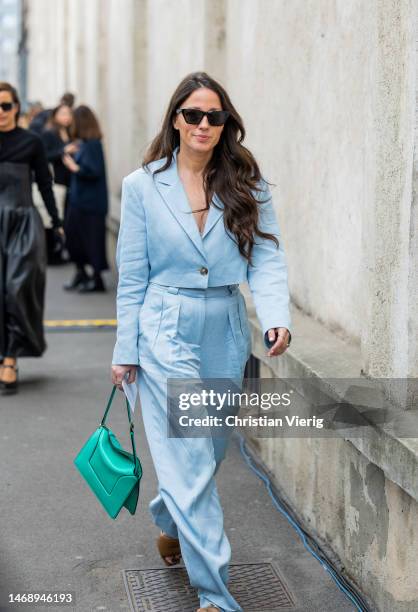 Guest wears satin turquoise suit, green bag outside Prada during the Milan Fashion Week Womenswear Fall/Winter 2023/2024 on February 23, 2023 in...