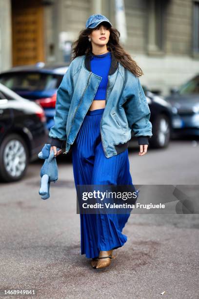 Guest is seen wearing a denim hat, a denim baseball oversized jacket with black details, a bright blue coord-set made of a crop-top sweaters and a...