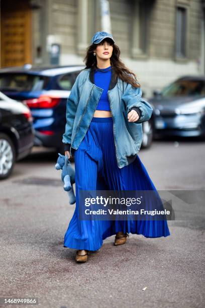 Guest is seen wearing a denim hat, a denim baseball oversized jacket with black details, a bright blue coord-set made of a crop-top sweaters and a...