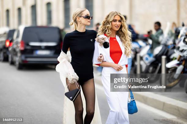 Leonie Hanne is seen wearing a black Prada body, triangle Prada bag, sunglasses and cream chiffon jacket, Emili Sindlev is seen wearing a white slit...