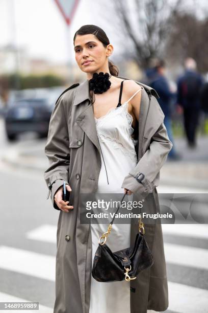 Guest is seen wearing a black choker embellished with a black fabric flower, a black bra, a beige long trench, a white long sleep-dress embellished...
