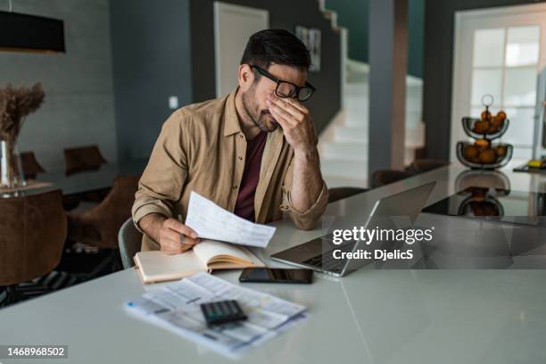 desperate young man working on his bills and having financial issues at home. - man crying stock pictures, royalty-free photos & images