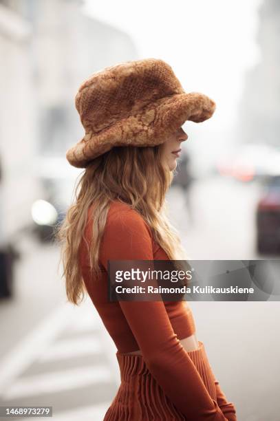 Guest is seen wearing an orange puffy fur hat, an orange turtleneck cropped, long-sleeved shirt, an orange long maxi skirt, black leather boots, and...