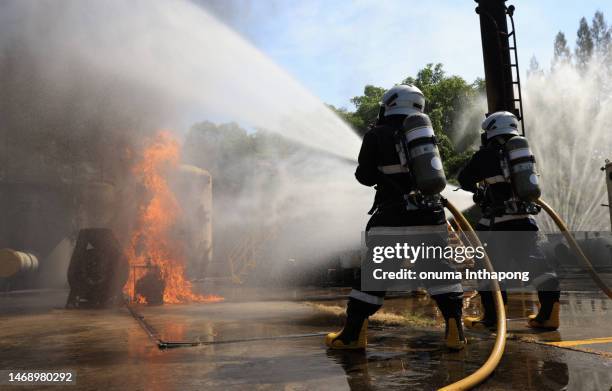 firefighters extinguishing hard working to fix fire ,fireman wearing firefighter turnouts and helmet. advant fire fighting and fire drill training - disaster relief stock pictures, royalty-free photos & images