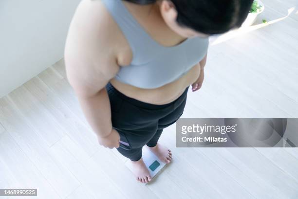 woman standing on weight scale - obesity stock pictures, royalty-free photos & images