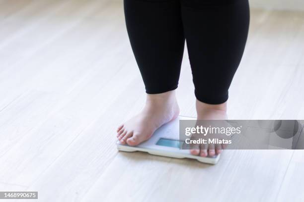 a woman's feet on a weight scale - weigh in stockfoto's en -beelden