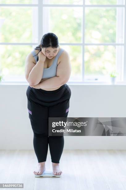 a woman thinking on a weight scale - metabolic syndrome stock pictures, royalty-free photos & images