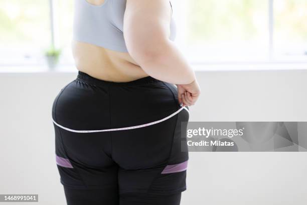 woman measuring her hip size with a tape measure - big bums fotografías e imágenes de stock