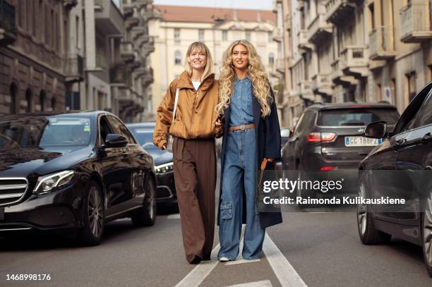 Jeanette Madsen wears a brown zipper jacket, and brown pants and Emili Sindlev wears a navy coat, denim bag, denim shirt, wide leg pants with side...