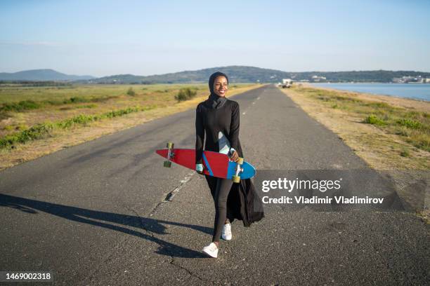 高速道路で一人でスケートボードを持つ女性 - ボード　持つ　女性 ストックフォトと画像