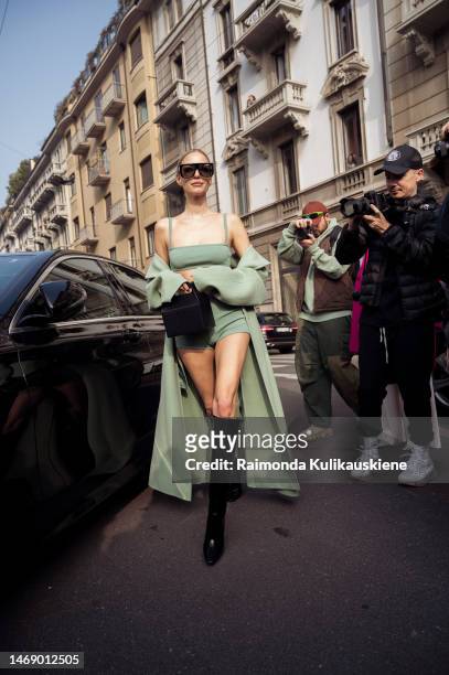 Leonie Hanne wears a green cropped top, shorts, coat, black YSL bag, and varnished boots outside the Max Mara show during the Milan Fashion Week...