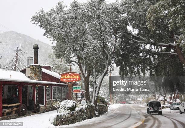 Snow falls above a restaurant in the San Gabriel Mountains, in San Bernardino County along the eastern border of Los Angeles County, on February 23,...