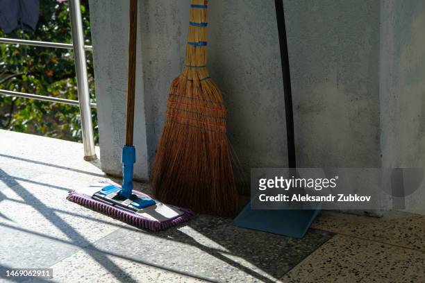 a broom, a dustpan for garbage against the wall in a clean room, in the pantry. a floor cleaning brush. cleaning at home, at work, in a public place. observance of order and compliance with hygiene standards. removal of dust and dirt in the building. - dustpan and brush fotografías e imágenes de stock