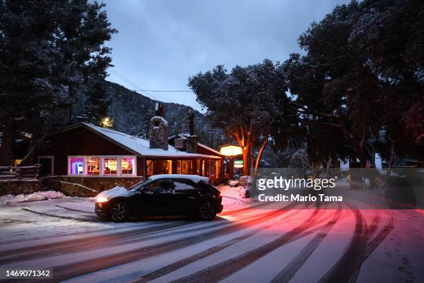 Car backs out next to a restaurant as snow blankets the town in the San Gabriel Mountains, in San Bernardino County along the border of Los Angeles...