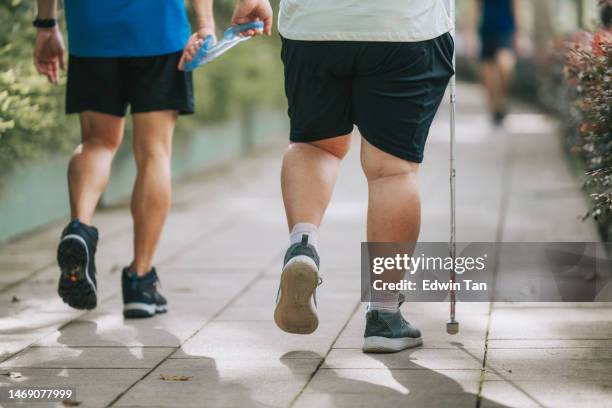 asian chinese visually impaired mature man holding running tether in public park with guide runner - kuit menselijk been stockfoto's en -beelden