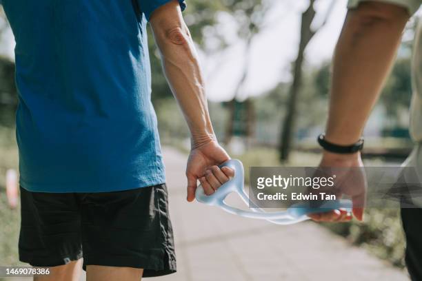 close up asian chinese visually impaired mature man holding running  tether in public park with guide runner - gift guide stockfoto's en -beelden