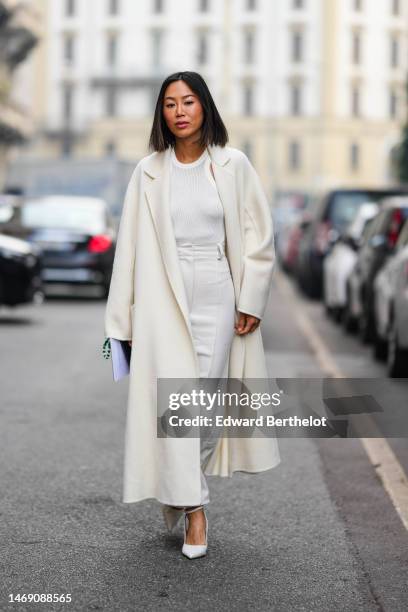 Aimee Song wears a white tank-top, a white long wool coat, a white ripped denim long skirt, white shiny leather pointed pumps heels shoes , outside...