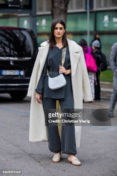Marta Lozano wears suit with white checkered print, fleece white coat, lavender bag, loafers outside Emporio Armani during the Milan Fashion Week...
