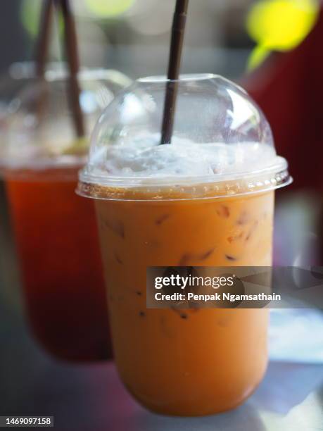 close up view of ice cubes in cold brewed iced tea thai in plastic cup put on desk blurred background, drink beverage - soft drink stock-fotos und bilder