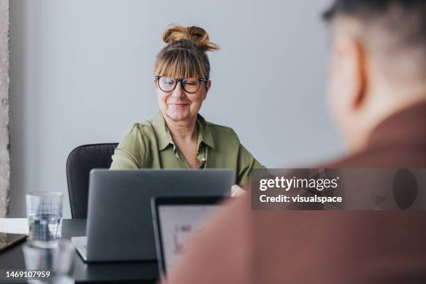 senior woman working in modern and bright office space. - estland stockfoto's en -beelden