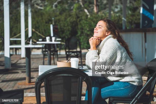 woman enjoying the sun in an sidewalk cafe - sidewalk cafe stock pictures, royalty-free photos & images