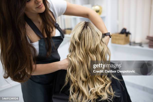 hairdresser blow drying female customers hair in hair salon. - hand holding hair dryer stock pictures, royalty-free photos & images