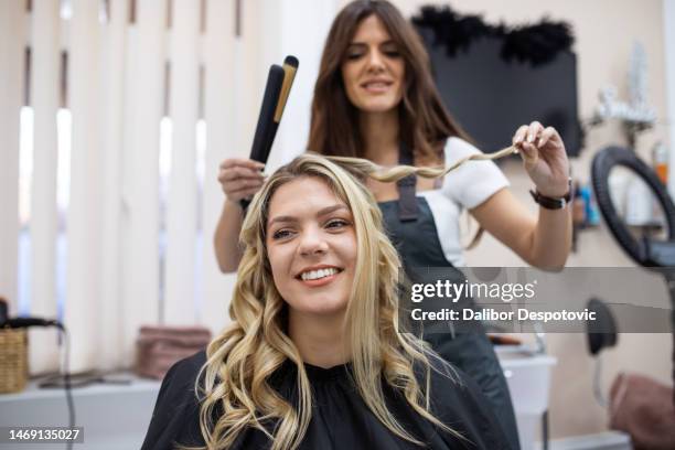 hairdresser blow drying female customers hair in hair salon. - drying hair stock-fotos und bilder