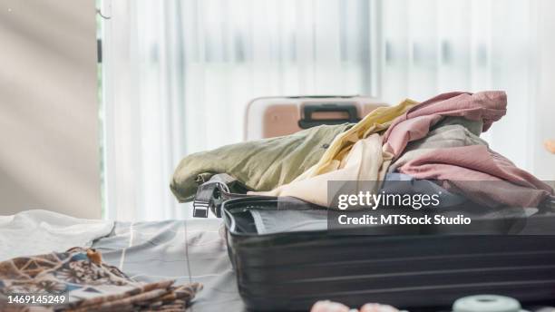 young asian female ready for holidays prepare suitcase throw cloth accessories messy stuff in bag in bedroom. travel vacation. - packed suitcase stock pictures, royalty-free photos & images