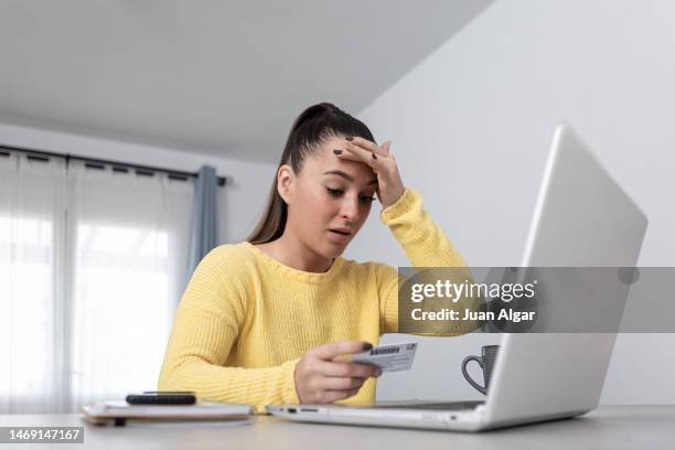 anxious woman with credit card shopping online - bank fraud stock pictures, royalty-free photos & images