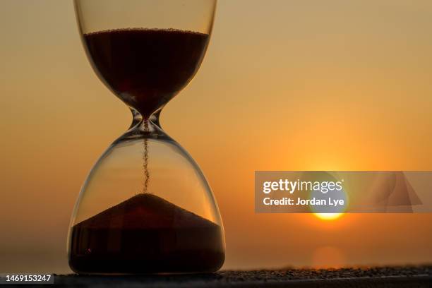 close-up of hourglass against sky during sunrise - reloj de arena fotografías e imágenes de stock